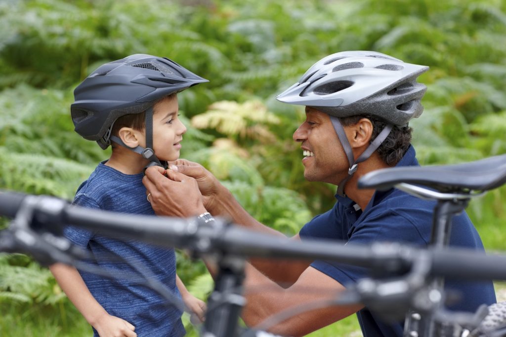 Man putting on a bike helmet for a child